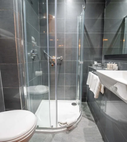 Modern hotel bathroom with sleek glass shower, elegant mirror, and plush towels for a luxurious stay.