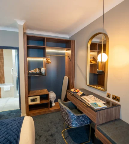 Elegant hotel room with plush bed, modern desk, cosy lighting, and spacious ensuite. Ideal for a relaxing stay.